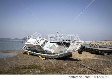 A ship lying askew on the sandy beach 64776950