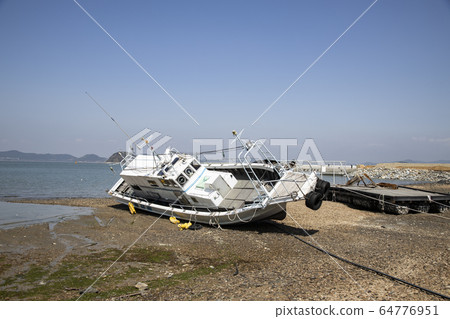 A ship lying askew on the sandy beach 64776951