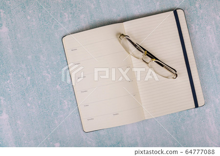 Overhead of notepad and Glasses on a desk Overhead of notepad and Glasses on a desk 64777088