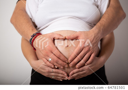 Cropped image of beautiful pregnant woman and her handsome husband hugging the tummy Cropped image of beautiful pregnant woman and her handsome husband hugging the tummy 64781501
