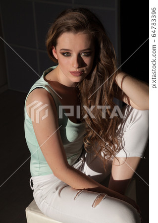 Beautiful fashionable woman with long hair sitting on the floor Beautiful fashionable woman with long hair sitting on the floor 64783396