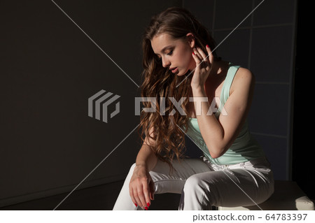 Beautiful fashionable woman with long hair sitting on the floor Beautiful fashionable woman with long hair sitting on the floor 64783397
