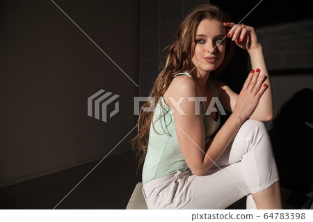 Beautiful fashionable woman with long hair sitting on the floor 64783398
