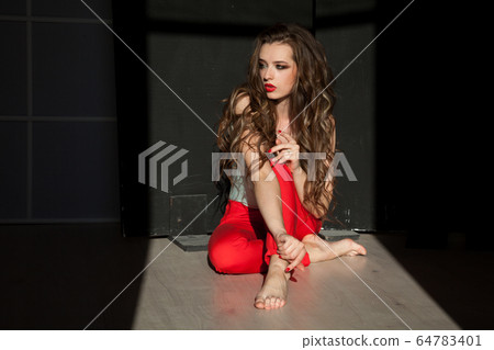 Beautiful fashionable woman with long hair sitting on the floor Beautiful fashionable woman with long hair sitting on the floor 64783401