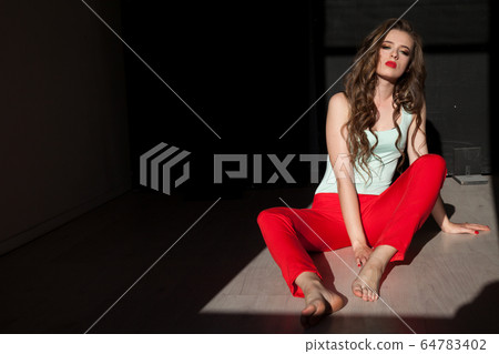 Beautiful fashionable woman with long hair sitting on the floor Beautiful fashionable woman with long hair sitting on the floor 64783402