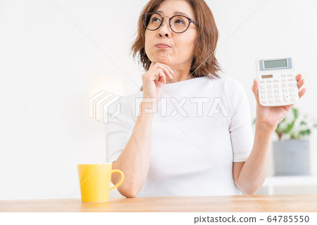Thinking senior woman with calculator 64785550