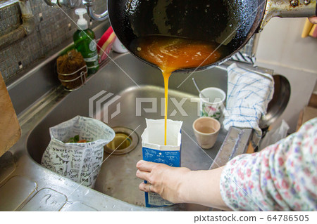 Housewife throwing waste oil into milk cartons 64786505