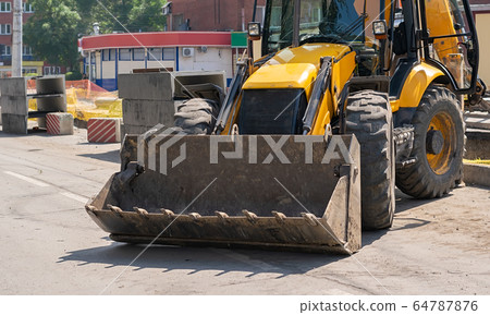 excavator on a city street where the road is being repaired 64787876
