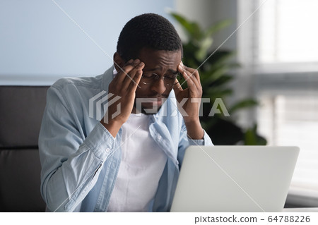 Unhappy african american businessman suffering from headache at work. Unhappy african american businessman suffering from headache at work. 64788226