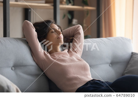 Carefree young beautiful housewife napping on couch. Carefree young beautiful housewife napping on couch. 64789010