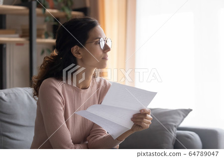 Thoughtful young attractive woman in glasses planning payout. 64789047