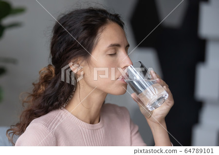 Peaceful calm millennial woman drinking glass of pure distilled aqua. Peaceful calm millennial woman drinking glass of pure distilled aqua. 64789101