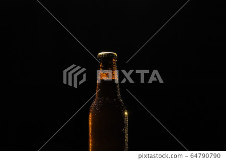 Bottle of beer with drops of water close-up on a black isolated background. 64790790