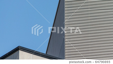 striped wall of a gray tall building against a blue sky 64790893