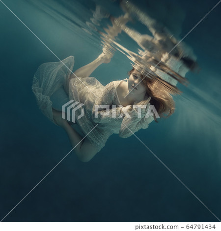Girl in a sequined dress swims underwater 64791434