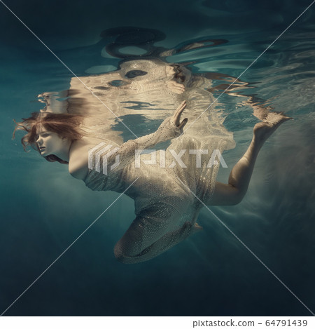 Girl in a sequined dress swims underwater Girl in a sequined dress swims underwater 64791439