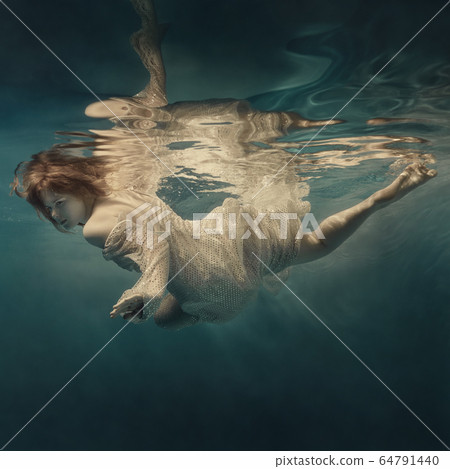 Girl in a sequined dress swims underwater 64791440