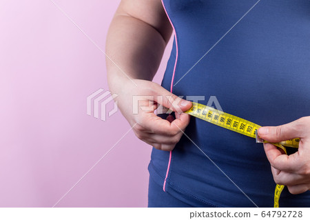 Overweight woman with measuring tape on waistline Overweight woman with measuring tape on waistline 64792728