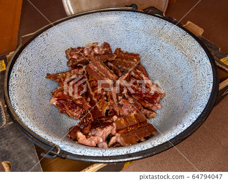 Meat broth in cauldron with cooked meat. 64794047