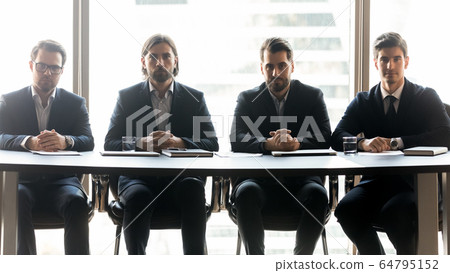 Four serious businessmen sitting in row at meeting Four serious businessmen sitting in row at meeting 64795152