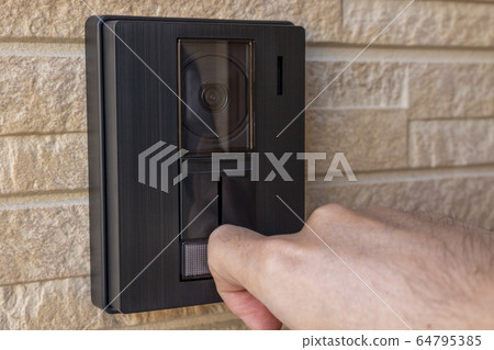 Man's hand bending his finger and pushing the button on the intercom 64795385