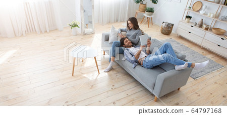 Young family of two relaxing on sofa at home 64797168