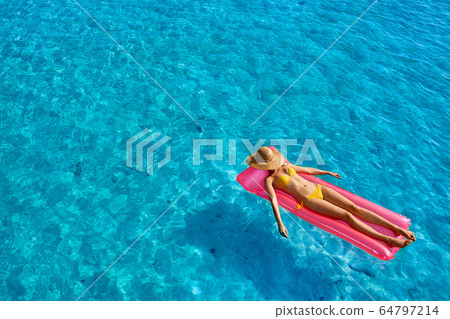 Woman relaxing on inflatable mat float Woman relaxing on inflatable mat float 64797214