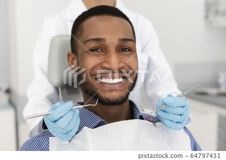 Portrait of smiling black man and dentist doctor hands 64797431