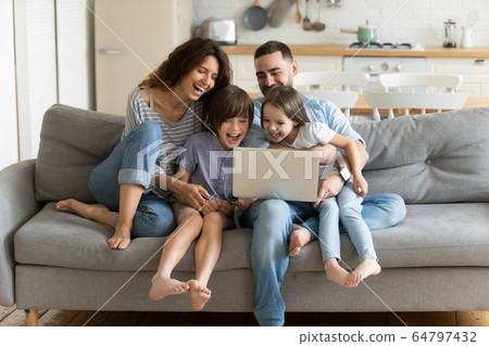 Overjoyed kids watching funny video on computer with parents. 64797432