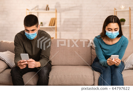 Couple wearing surgical mask using cell phones 64797622