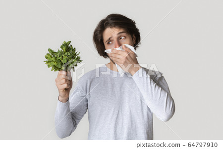 Man fighting with spring allergies and covers nose Man fighting with spring allergies and covers nose 64797910