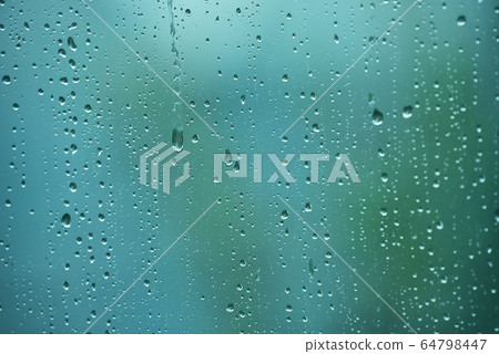 雨滴在新鮮的綠色春天綠色窗戶的背景下流動。 64798447