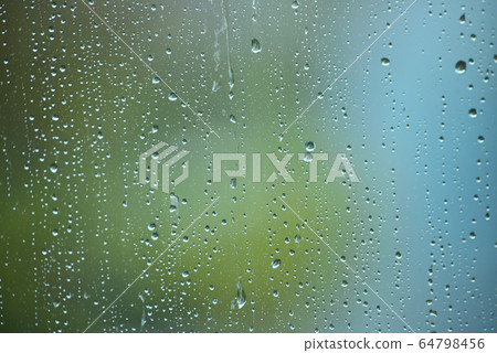 殭屍的雨滴在春天綠色的背景下從窗戶流下。 64798456