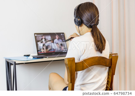 Social distancing woman wearing headphone during group video call with friends. 64798734
