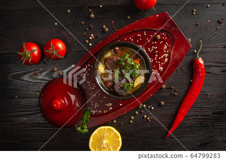 vegetable stew with potatoes and meat in a pot on a dark wooden background 64799283