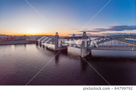 St. Petersburg Russia. Aerial panoramic view from drone to Peter the Great bridge of white nights. Bolsheokhtinsky bridge across the river Neva with evening lighting city with driving cars on highway. St. Petersburg Russia. Aerial panoramic view from drone to Peter the Great bridge of white nights. Bolsheokhtinsky bridge across the river Neva with evening lighting city with driving cars on highway. 64799792