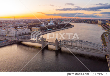 St. Petersburg Russia. Aerial panoramic view from drone to Peter the Great bridge of white nights. Bolsheokhtinsky bridge across the river Neva with evening lighting city with driving cars on highway. St. Petersburg Russia. Aerial panoramic view from drone to Peter the Great bridge of white nights. Bolsheokhtinsky bridge across the river Neva with evening lighting city with driving cars on highway. 64799793