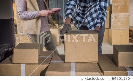 The truck puts boxes of goods in the car, a woman with a tablet works nearby The truck puts boxes of goods in the car, a woman with a tablet works nearby 64801120