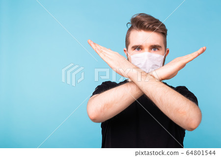 Stop the infection and pandemic. Healthy man showing gesture stop. Photo of man wear protective mask against infectious diseases, flu and covid-19. Health care and coronavirus concept. Blue background 64801544