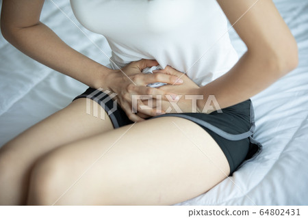 woman have bladder pain and stomach ache sitting on bed in bedroom 64802431