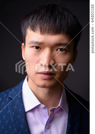 Portrait of young Chinese businessman against gray background Portrait of young Chinese businessman against gray background 64803188