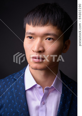 Portrait of young Chinese businessman against gray background Portrait of young Chinese businessman against gray background 64803190