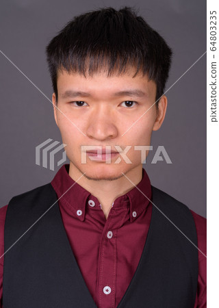 Portrait of young Chinese businessman against gray background Portrait of young Chinese businessman against gray background 64803235