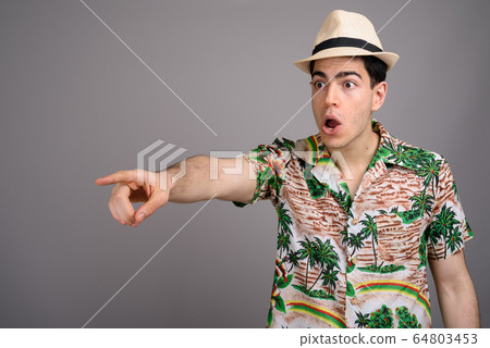 Young handsome tourist man ready for vacation against gray backg 64803453