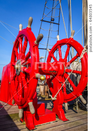 Red wheel helm on antique ship Red wheel helm on antique ship 64803545