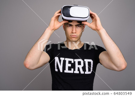 Young handsome nerd man wearing virtual reality headset Young handsome nerd man wearing virtual reality headset 64803549
