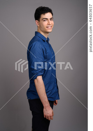 Portrait of young handsome businessman against gray background Portrait of young handsome businessman against gray background 64803657