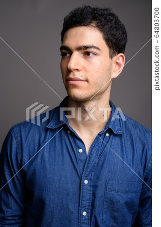 Portrait of young handsome businessman against gray background Portrait of young handsome businessman against gray background 64803700