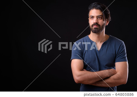 Portrait of handsome bearded Persian man thinking with arms crossed 64803886