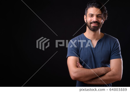 Portrait of happy handsome bearded Persian man smiling with arms crossed 64803889